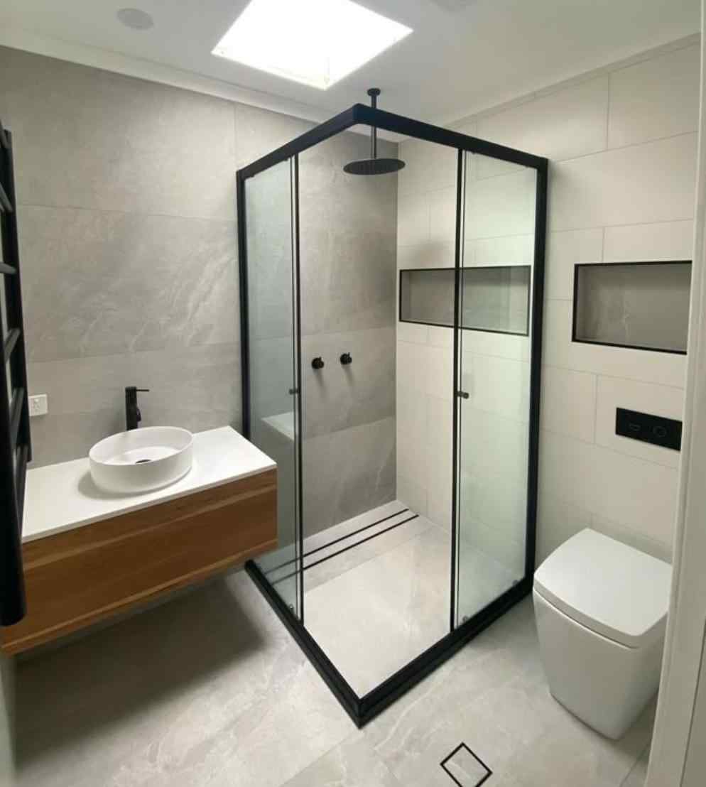 Modern bathroom with a black-framed glass shower, floating wood vanity and vessel sink