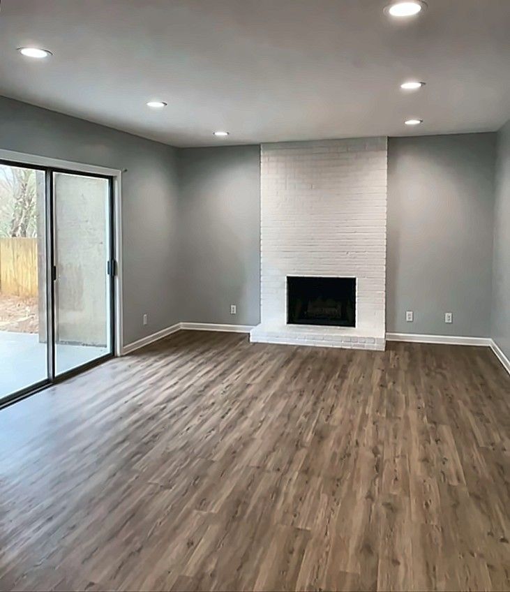 Renovated family room with white brick fireplace and vinyl plank flooring